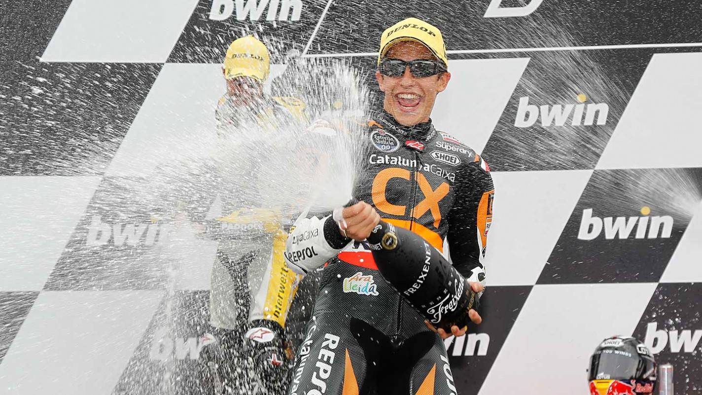 Piloto Marc Marquez no pódio jogando champanhe com garrafa nas mãos
