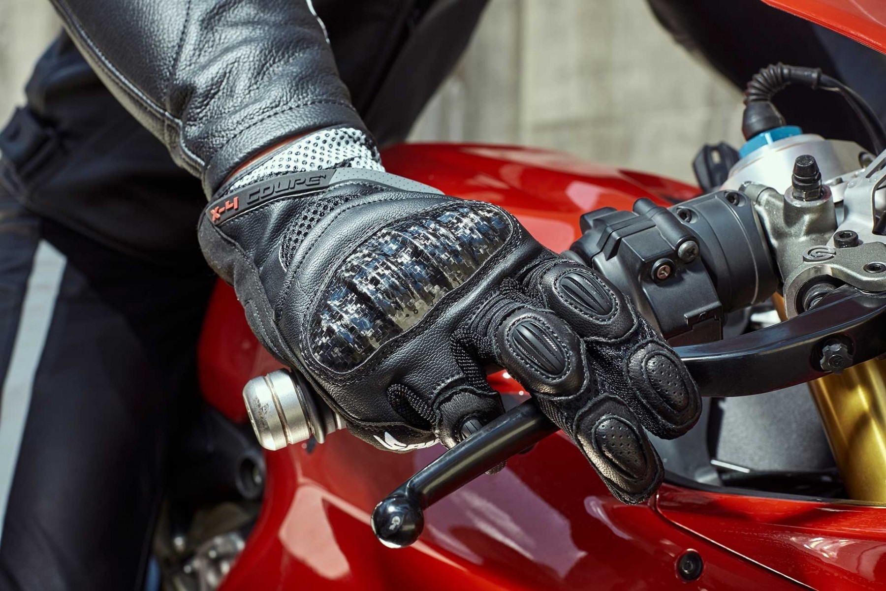 Pessoa com luva de moto segurando freio no guidão de motocicleta