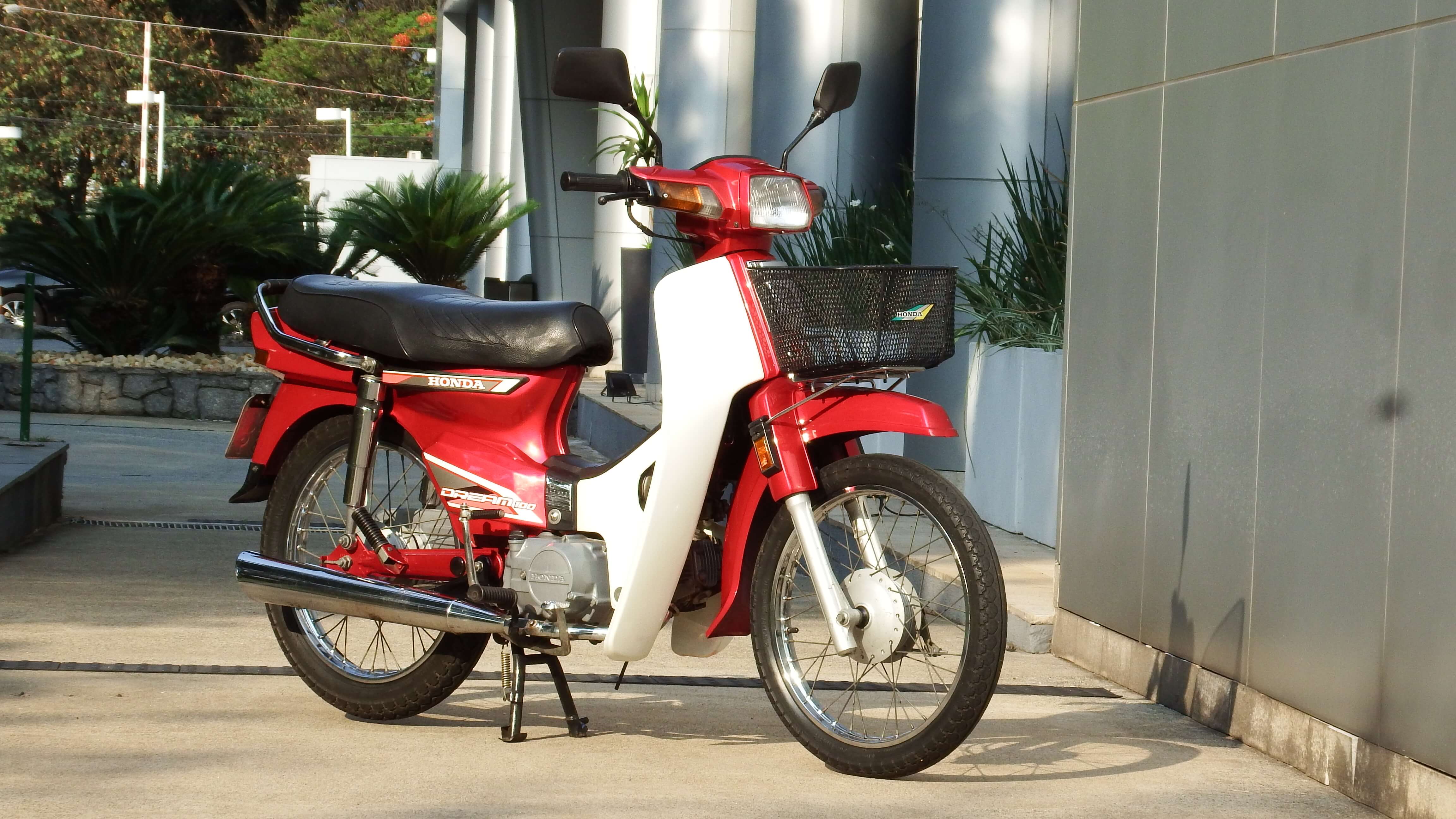 Moto Honda C100 Dream vermelha e branca no cavalete