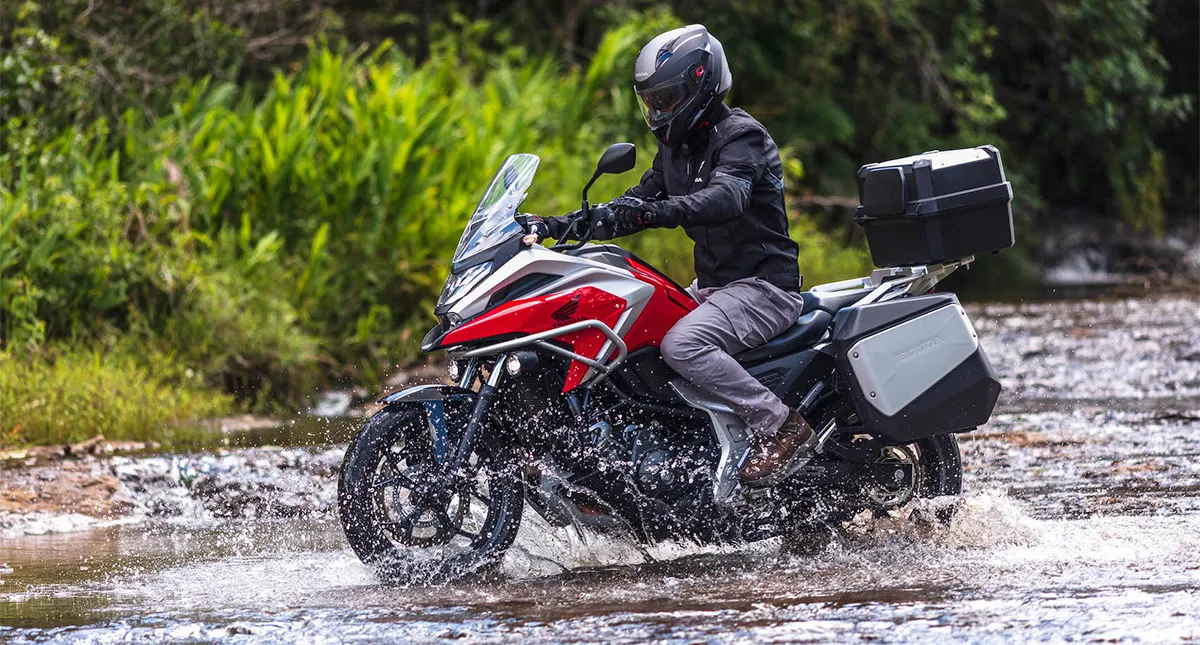 Piloto com sua Moto Honda NC 750X atravessando rio