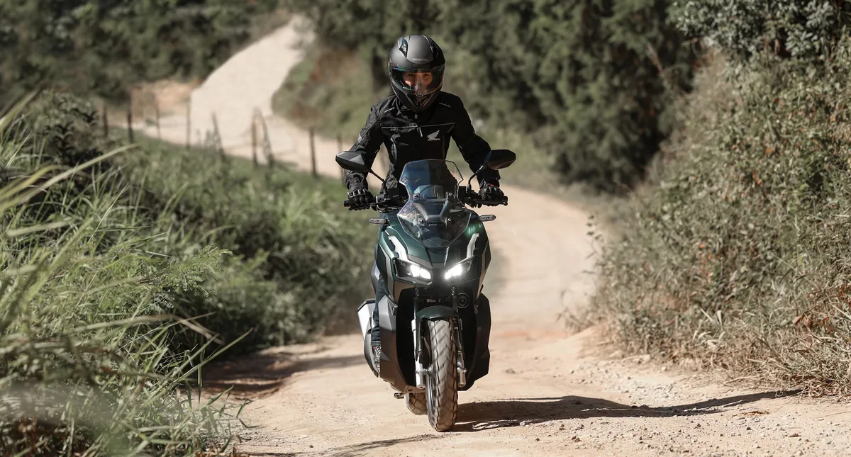 Piloto em sua Scooter Honda ADV em estrada de terra