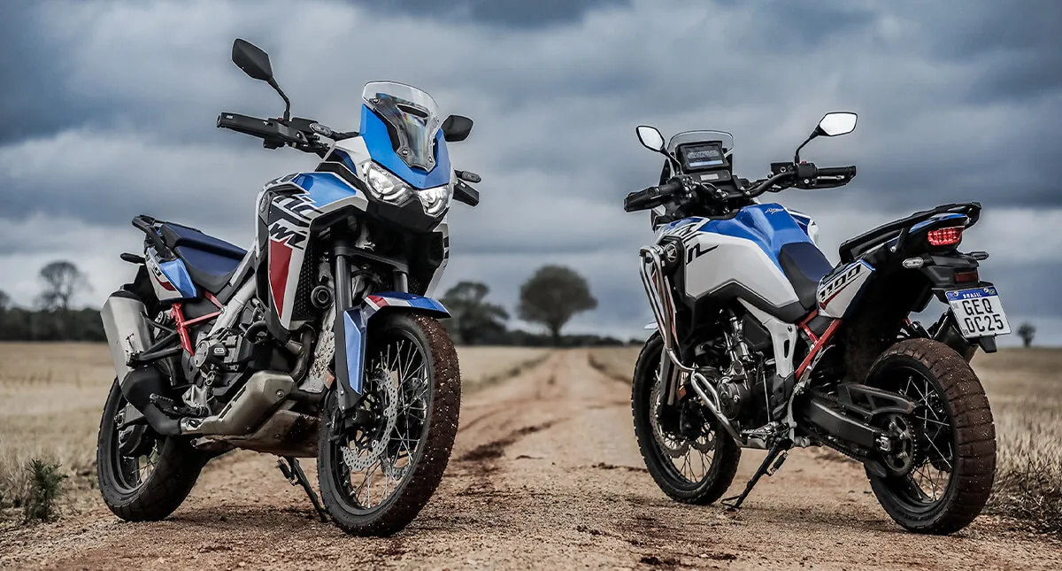 Duas motocicletas Africa Twin paradas uma de frente e a outra de costas em estrada de terra