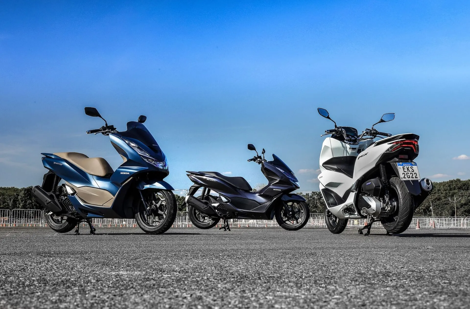 Três PCX Honda estacionadas, duas azuis e uma branca