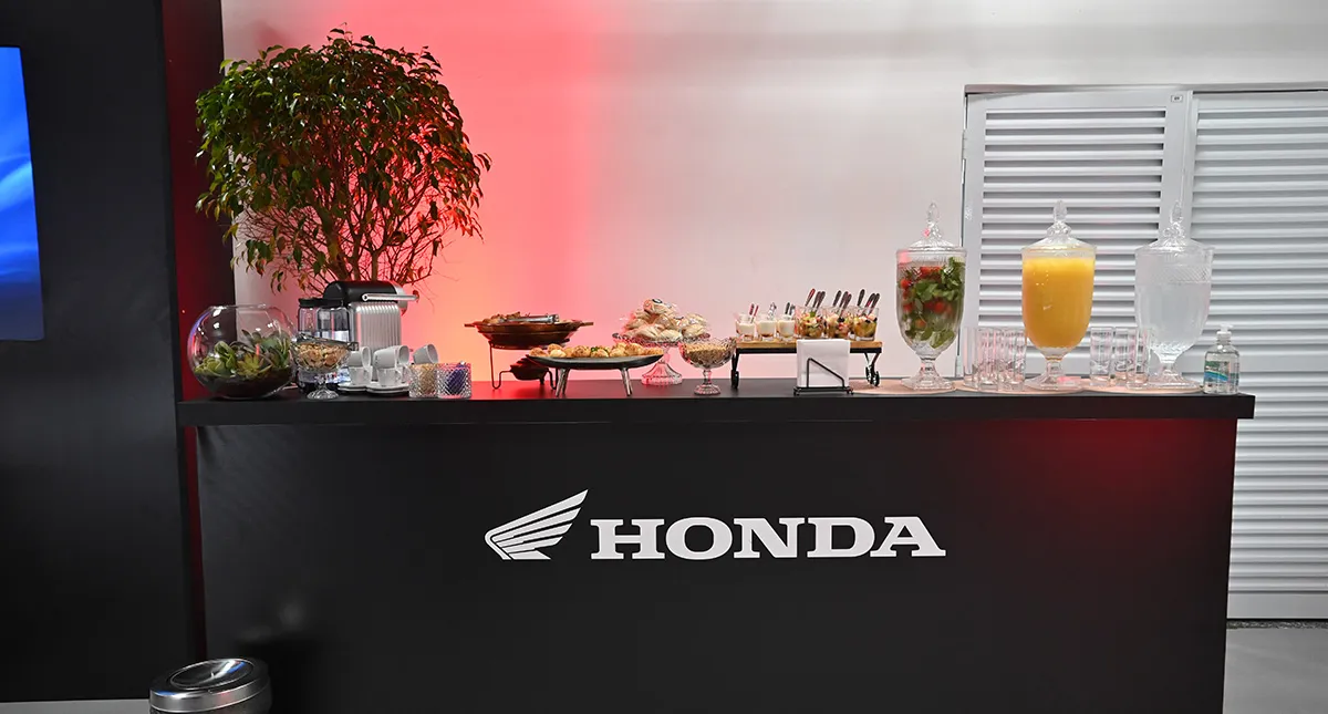 Ambiente interno da área vip da Honda com balcão servindo alimentos