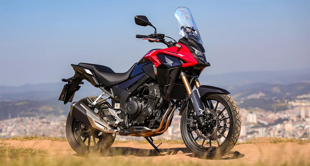 Motocicleta Honda CB 500X vermelha com paisagem de cidade ao fundo