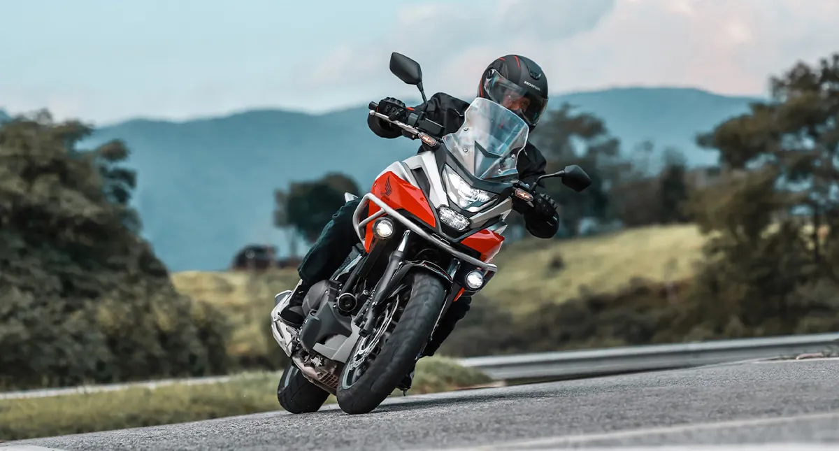 Piloto em sua Honda NC 750X fazendo curva na estrada