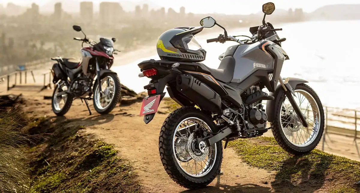 Novas Honda XRE 190 cinza e vermelha com praia ao fundo